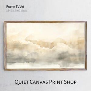 May include: A framed digital art print featuring a watercolor landscape in shades of beige, brown, and gray. The artwork depicts a cloudy sky or mountain range. The frame is made of light-colored wood. The text "Frame TV Art" and "QUIET CANVAS PRINT SHOP" are visible.