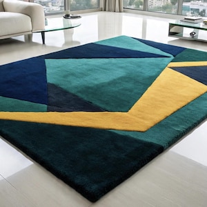 May include: A rectangular area rug with a geometric design. The rug features a pattern of blue, teal, and yellow shapes. The rug is made of a soft, plush material and is suitable for a living room or bedroom.