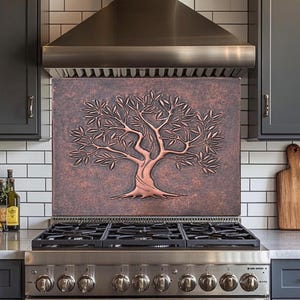 May include: Copper-toned kitchen splashback featuring a detailed tree relief. The tree's branches and leaves are intricately designed, set against a textured background. The splashback is mounted above a stainless steel gas hob in a modern kitchen.