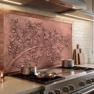 Könnte beinhalten: Kupferfarbene Küchenrückwand mit einem erhabenen Astdesign. Die Küche verfügt über einen Kupferkessel, Töpfe und eine Pfanne auf einem Edelstahlherd. Die Rückwand ist von einem Kupferrahmen umgeben.