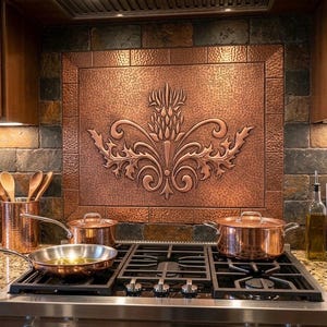 May include: A copper kitchen backsplash with an embossed floral design is the focal point of this kitchen. Copper pots and pans sit on a gas stove. Wooden utensils are in a copper container. The kitchen has a rustic, warm feel.