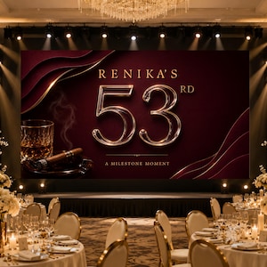 May include: A large digital display screen featuring the text RENIKA'S 53RD A MILESTONE MOMENT in gold lettering against a deep burgundy background with abstract curves, a glass of amber liquid, and a cigar resting in an ashtray.