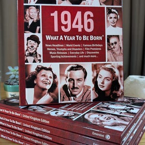 K&ouml;nnte beinhalten: Ein gebundenes Buch mit dem Titel 1946 What A Year To Be Born, das auf dem Einband eine Collage aus schwarz-wei&szlig;en Prominentenportr&auml;ts zeigt. Der Text listet historische Kategorien auf, darunter News Headlines, World Events und Famous Birthdays. Ein Stapel identischer B&uuml;cher ist darunter zu sehen.