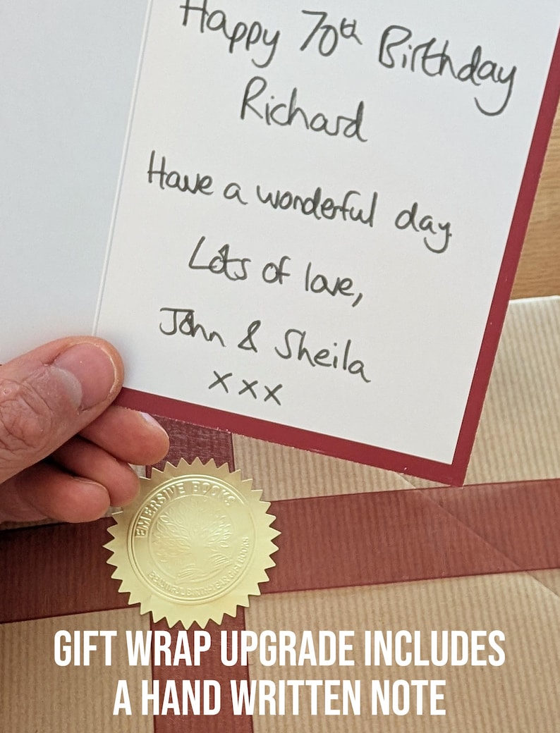 K&ouml;nnte beinhalten: Eine wei&szlig;e Gru&szlig;karte mit dunkelrotem Rand und handgeschriebenem Text in schwarzer Tinte: Happy 70th Birthday Richard, Have a wonderful day, Lots of love, John & Sheila, xxx. Die Karte liegt auf einem braun verpackten Geschenk.