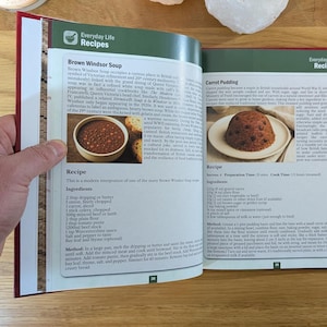 K&ouml;nnte beinhalten: Ein aufgeschlagenes Kochbuch mit dem Titel Everyday Life Recipes mit zwei Seiten. Die linke Seite zeigt ein Rezept f&uuml;r Brown Windsor Suppe mit einer Suppensch&uuml;ssel und Text. Die rechte Seite zeigt ein Karottenpudding-Rezept.