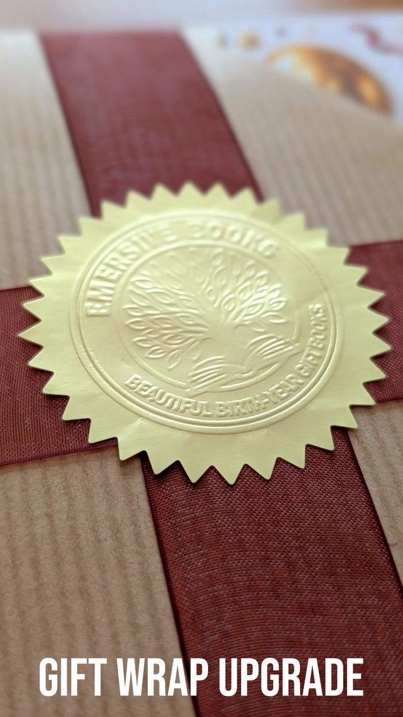 K&ouml;nnte beinhalten: Ein braunes Geschenkpapierpaket mit einem dunkelroten Band in Kreuzform, verziert mit einem runden goldenen Foliensiegel. Das Siegel zeigt ein gepr&auml;gtes Baummotiv und den Text EMERSIVE BOOKS BEAUTIFUL BIRTH-YEAR GIFT BOOKS.