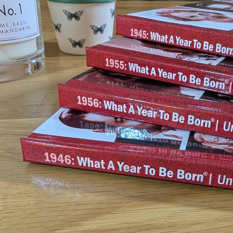 K&ouml;nnte beinhalten: Ein Stapel aus vier roten Hardcover-B&uuml;chern mit wei&szlig;em Text auf den Buchr&uuml;cken. Jeder Buchr&uuml;cken zeigt das Jahr gefolgt vom Titel: 1945: What A Year To Be Born, 1955: What A Year To Be Born, 1956: What A Year To Be Born und 1946: What A Year To Be Born.