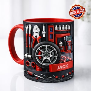 May include: A red-handled mug with a black exterior featuring a 3D design of automotive tools and a tire. The interior of the mug is red. The name "JACK" is printed on a red rectangle. A "Made in USA" sticker is visible.