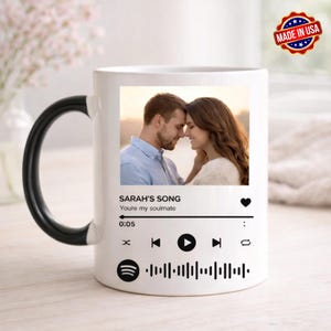 May include: White ceramic mug with a black handle featuring a photo of a couple. The mug has the text "SARAH'S SONG" and "You're my soulmate" with a music player interface design. A "Made in USA" sticker is visible.