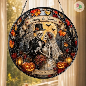 Peut inclure: Un attrape-soleil circulaire en vitrail représentant un couple de squelettes en tenue de mariage, avec le texte Emily & James et October 26, 2024. Le motif inclut des feuilles d'automne, des citrouilles, une pleine lune et des chauves-souris.