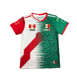 May include: A short-sleeve t-shirt featuring a split design of red, white, and green. The front displays the flags of Peru and Mexico with their respective names, alongside a large, dark green circular Aztec calendar graphic and the text MEXICO.
