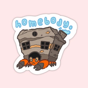 May include: A cartoon sticker of a crab carrying a house on its back. The house is gray and has windows. The crab is orange and has a sad expression. The text "homebody" is written in blue above the crab.