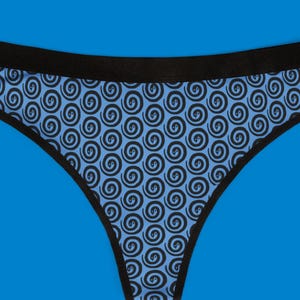 Könnte beinhalten: Blauer String-Tanga mit einem sich wiederholenden schwarzen Spiralmuster. Der Bund und die Kanten sind schwarz eingefasst. Der Hintergrund ist einfarbig blau.