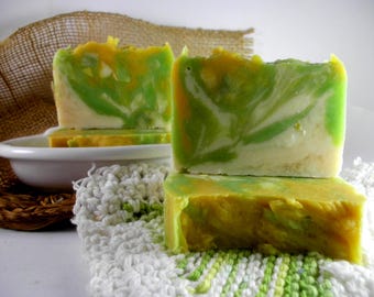 May include: Two rectangular bars of handmade soap featuring a marbled swirl pattern in shades of bright yellow, lime green, and creamy white. The soap bars have a smooth, solid texture with visible color blending throughout the surface of each piece.