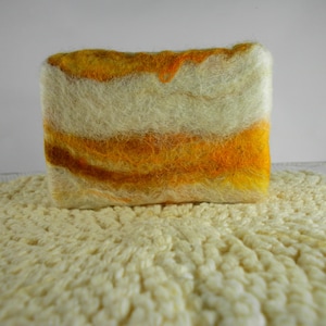 May include: A handmade soap bar with a white and yellow marbled design. The soap is made with natural ingredients and is perfect for sensitive skin.