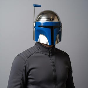 May include: A metallic silver and blue helmet with a vertical antenna. The helmet has a blue visor and a silver dome. The person is wearing a gray zip-up jacket.