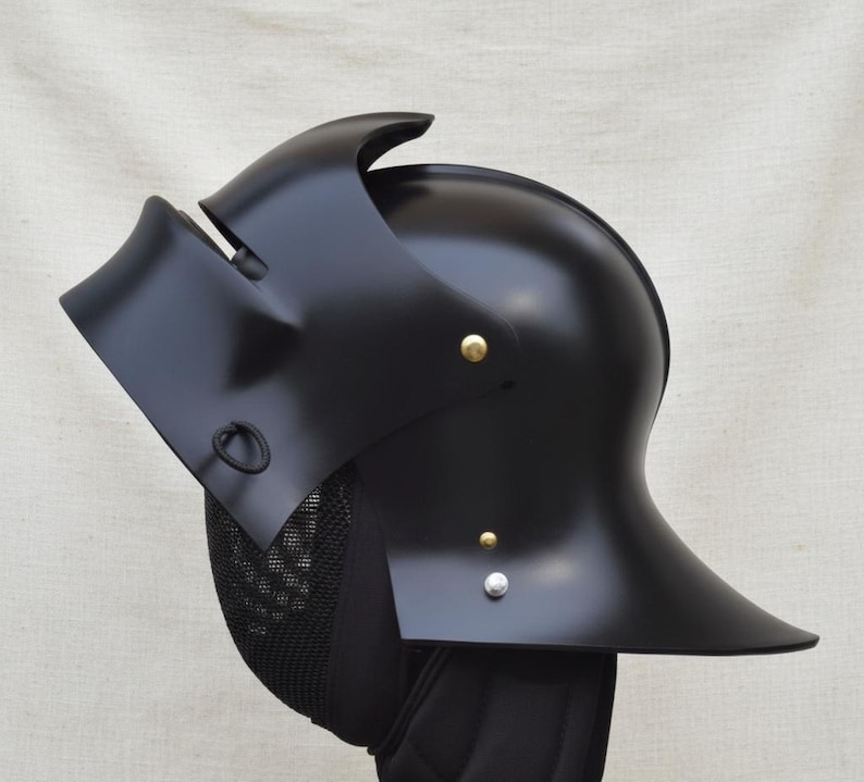 May include: A black metal helmet with a curved visor and a rounded top. The helmet has a series of rivets and a mesh guard. The helmet is likely for historical reenactment or display.