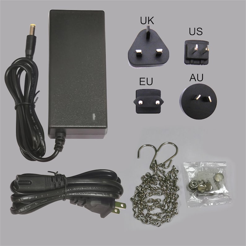 May include: A black power adapter with various plug types labeled UK, US, EU, and AU. Includes a power cord, a metal chain, and a small bag of hardware. The items are arranged on a light gray background.