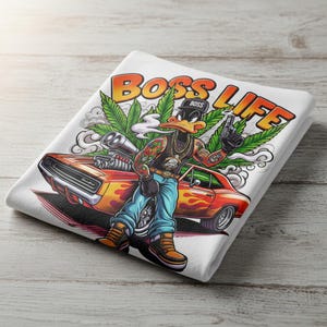 May include: White t-shirt featuring a cartoon duck with tattoos, a gold chain, and a black hat that says "BOSS". The duck is smoking and holding a gun, with a red car and the words "BOSS LIFE" in orange.