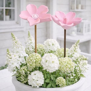 Może przedstawiać: Biały ceramiczny kubek z czarnym uchwytem i napisem "But First, Coffee" pogrubioną czcionką. Kubek jest umieszczony na rozmytym tle, sugerującym przytulne otoczenie.