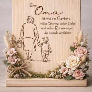 May include: Wooden plaque with engraved text in German, "Eine Oma ist wie ein Garten..." featuring an illustration of a grandmother and child. The plaque is decorated with dried flowers and roses in shades of pink and cream.