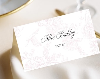 May include: A folded white place card with the name "Allie Bakley" in elegant script and "TABLE 1" printed below. The card features a delicate pink floral and bird design.