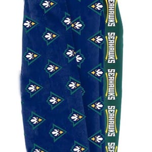 May include: A pair of blue socks with a repeating pattern of white and green floral designs. The top band is green with the word "SEAHAWKS" in white. These socks are likely for a sports fan.