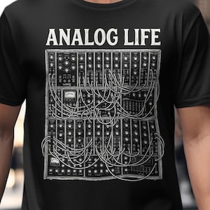 以下が含まれることがあります： 「ANALOG LIFE」の文字と、モジュラーシンセサイザーの白黒イラストが描かれた黒いTシャツ。複雑な配線と楽器の部品が詳細に描かれています。