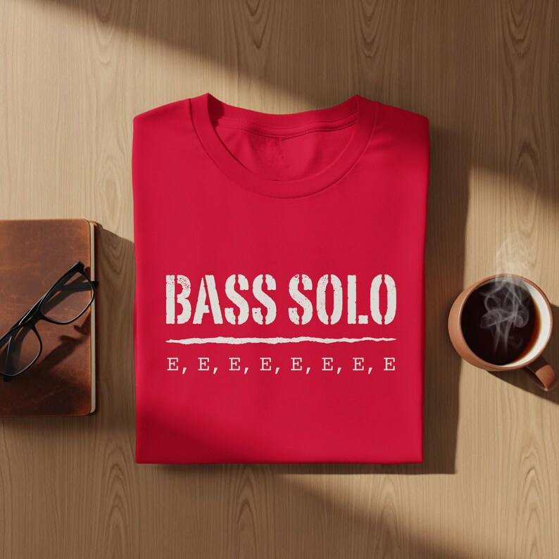 Red t-shirt with "BASS SOLO" and musical notes on a wooden surface.
