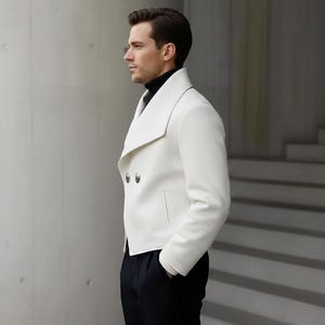 May include: A white double-breasted jacket with silver buttons and a wide lapel. The jacket has a tailored fit and is paired with dark navy pants. The person is wearing a black turtleneck. The jacket has a classic, modern design.