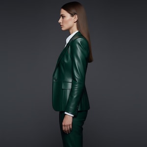 May include: A dark green leather blazer with a single-button closure, paired with matching pants. The blazer features a classic lapel and a tailored fit. A white collared shirt is visible underneath. The outfit is set against a dark gray background.
