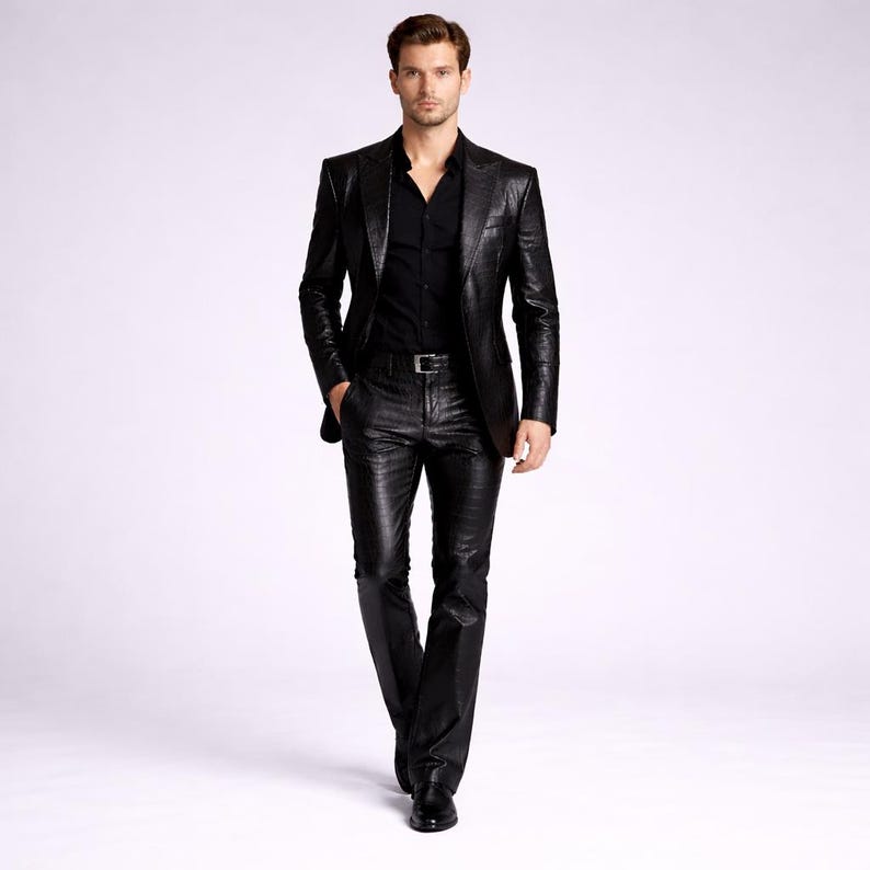 May include: A black leather suit, including a blazer and matching pants, is worn with a black button-down shirt. The suit has a textured appearance and is paired with a silver belt and black shoes. The outfit is set against a plain white background.
