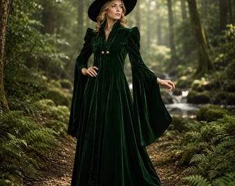 May include: A floor-length dark green velvet dress with long flared sleeves, a high collar, and two gold buttons at the chest. The garment is paired with a wide-brimmed black pointed hat, creating a cohesive ensemble with a structured silhouette.