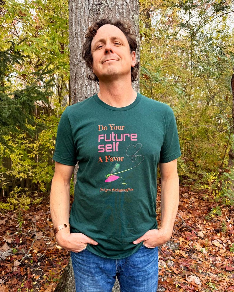 Puede incluir: Una camiseta verde oscuro con el texto "Do Your Future Self A Favor" en rosa y blanco. La camiseta presenta un gr&aacute;fico de una lib&eacute;lula y las palabras "You'll get to thank yourself later."