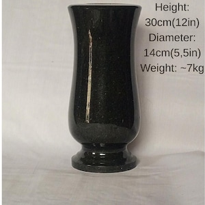 May include: A black Ukrainian Black Gabbro vase. The vase is 12 inches tall, 5.5 inches in diameter, and weighs approximately 15.4 pounds. The vase has a flared top and a pedestal base.