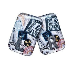 Könnte beinhalten: Zwei rechteckige, transparente Dekorationsartikel mit medizinischen Motiven. Einer zeigt den Buchstaben "L" und der andere "R". Jeder hat ein Röntgenbild, ein Strahlungssymbol und einen Regenbogen.