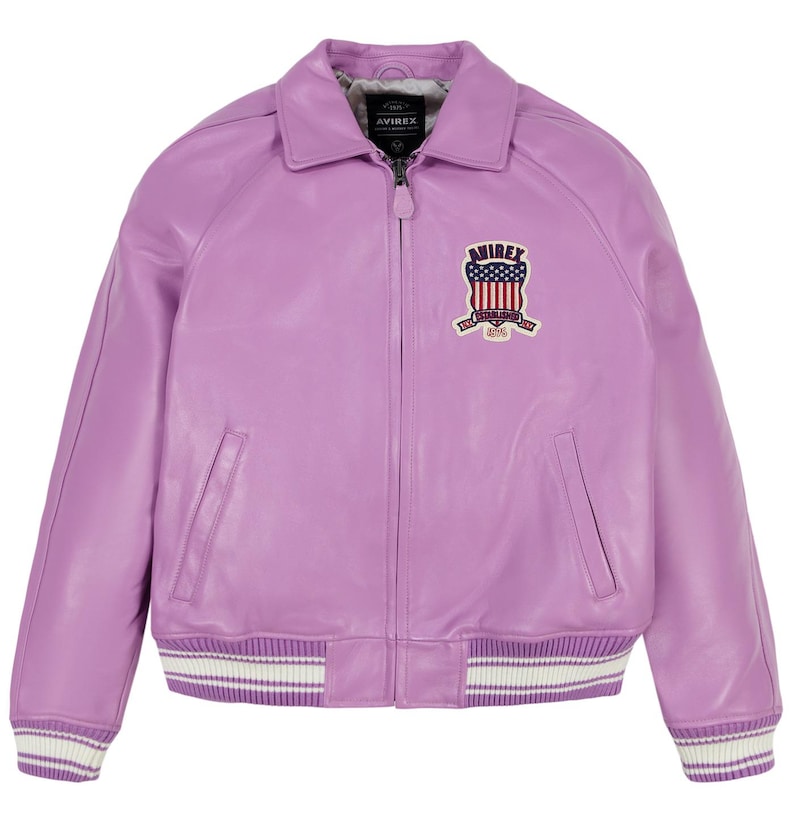 May include: A lavender leather jacket with a classic bomber style. Features a collared neckline, a zipper closure, and a patch on the chest with a shield design. The cuffs and hem have white and purple striped detailing.