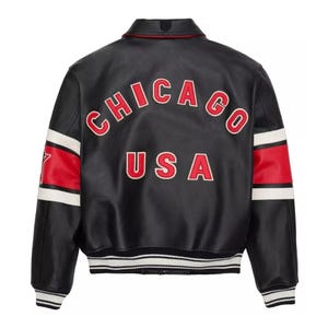 May include: Black leather jacket with the word "CHICAGO" arched across the back in red lettering with a white outline, above "USA". The sleeves have red and white stripes. The jacket has a white and black striped hem.
