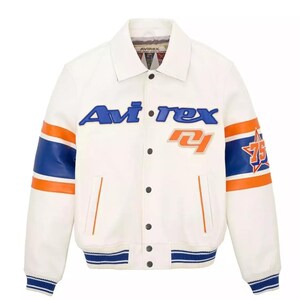 May include: A white leather jacket with blue and orange accents. The jacket features the brand name "Avi-rex" in blue lettering across the chest, along with the number "75" and a star graphic on the sleeve. The sleeves have blue and orange stripes.