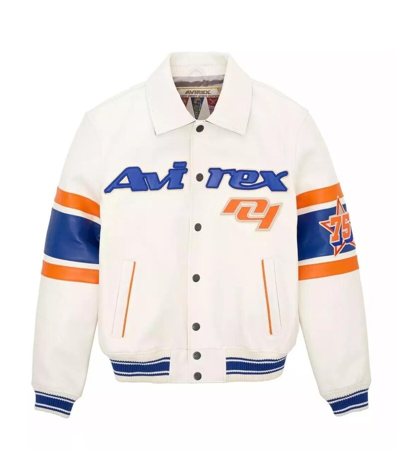 May include: A white leather jacket with blue and orange accents. The jacket features the brand name "Avi-rex" in blue lettering across the chest, along with the number "75" and a star graphic on the sleeve. The sleeves have blue and orange stripes.