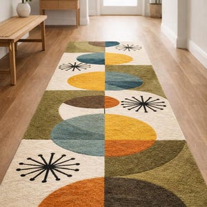 May include: A rectangular area rug with a mid-century modern design. The rug features a cream-colored background with geometric shapes in olive green, brown, orange, yellow, and blue. Black starburst patterns are also present.