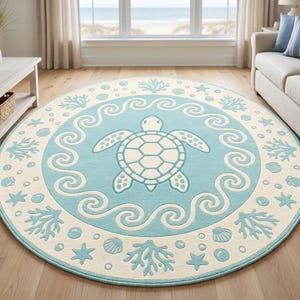 May include: Circular rug with a sea turtle motif. The rug has a light blue central area with a white turtle and wave design. The border is off-white, featuring coral, starfish, and seashell patterns. A coastal theme.