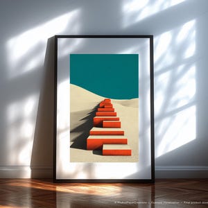 May include: Framed art print featuring a minimalist landscape. A series of orange steps ascend a sandy dune towards a teal sky. The artwork is framed in a black border, creating a striking contrast against the white wall.