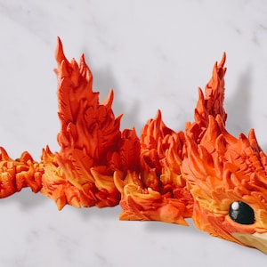 May include: A detailed, orange and yellow dragon sculpture with a fiery appearance. The dragon has a detailed head with a black eye and a beak, and its body is composed of flame-like structures. The sculpture is likely a fantasy-themed decorative item.