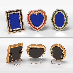 May include: Six miniature picture frames, three with blue backgrounds and gold trim, and three with black backgrounds and gold trim. The frames are in different shapes, including a rectangle, heart, and oval. The frames with black backgrounds have a stand on the back.