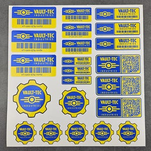 May include: A sheet of Vault-Tec Industries stickers in various sizes and shapes. The stickers feature a blue and yellow colour scheme with the Vault-Tec logo and text. Some stickers include barcodes and the text "VT-UAV-076-4493".