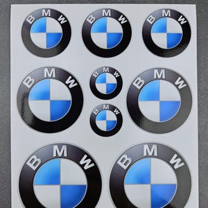 May include: A sheet of BMW logo stickers. The stickers display the BMW emblem, a circular design with a black border, the letters "BMW" and a blue and white quadrant pattern. Various sizes are included.