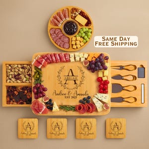 May include: A bamboo charcuterie board set with a variety of cheeses, meats, fruits, and nuts. The board is engraved with the names "Andrew & Amanda" and "EST 2025" along with the name "Abigail". Includes serving utensils and coasters.
