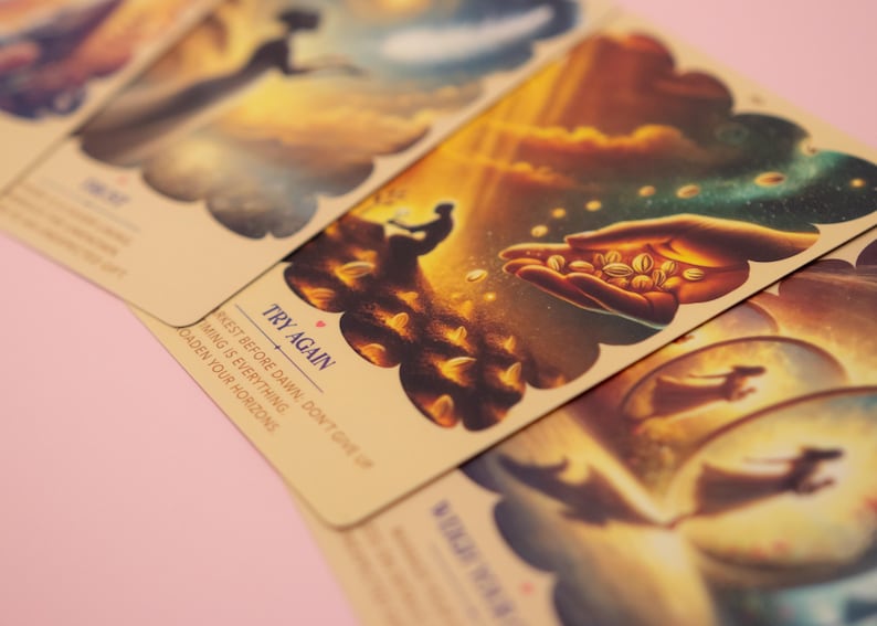 Puede incluir: Un conjunto de cartas de or&aacute;culo rectangulares con esquinas redondeadas, con ilustraciones en tonos c&aacute;lidos de figuras y manos. Una carta muestra el texto TRY AGAIN, junto a la frase THE DARKEST BEFORE DAWN; TIMING IS EVERYTHING. BROADEN YOUR HORIZONS.