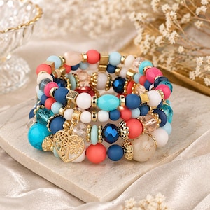 Peut inclure: Plusieurs bracelets de perles colorées, rouges, bleues, blanches et turquoise. Les bracelets comportent des éléments dorés et un charm en forme de cœur. Les perles sont de différentes formes et tailles.